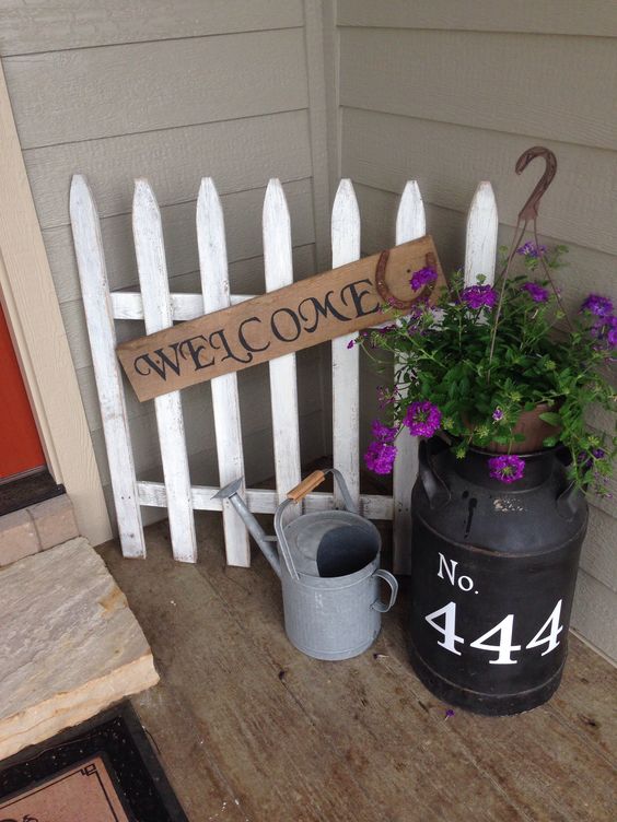 Farmhouse Style Porch Decorated With Old Picket Fence And Antique Milk Can. 